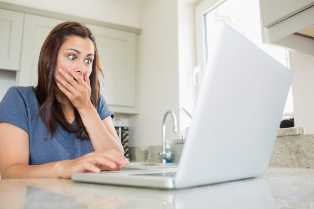 Woman shocked at laptop in kitchen