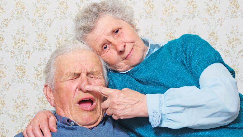 older woman sitting on husbands lap poking his nose