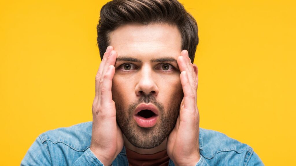 Man holding his face looking shocked