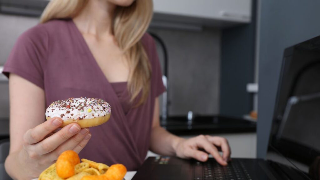 Eating Habits woman sitting at the computer holding a donut