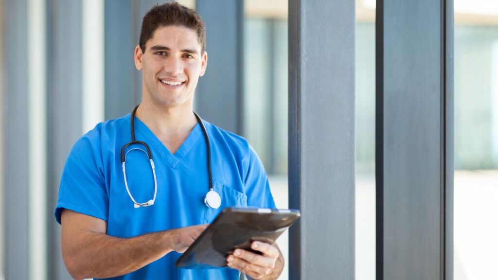 The Nursing Profession: man standing with a clipboard dressed in scrubs as a nurse.