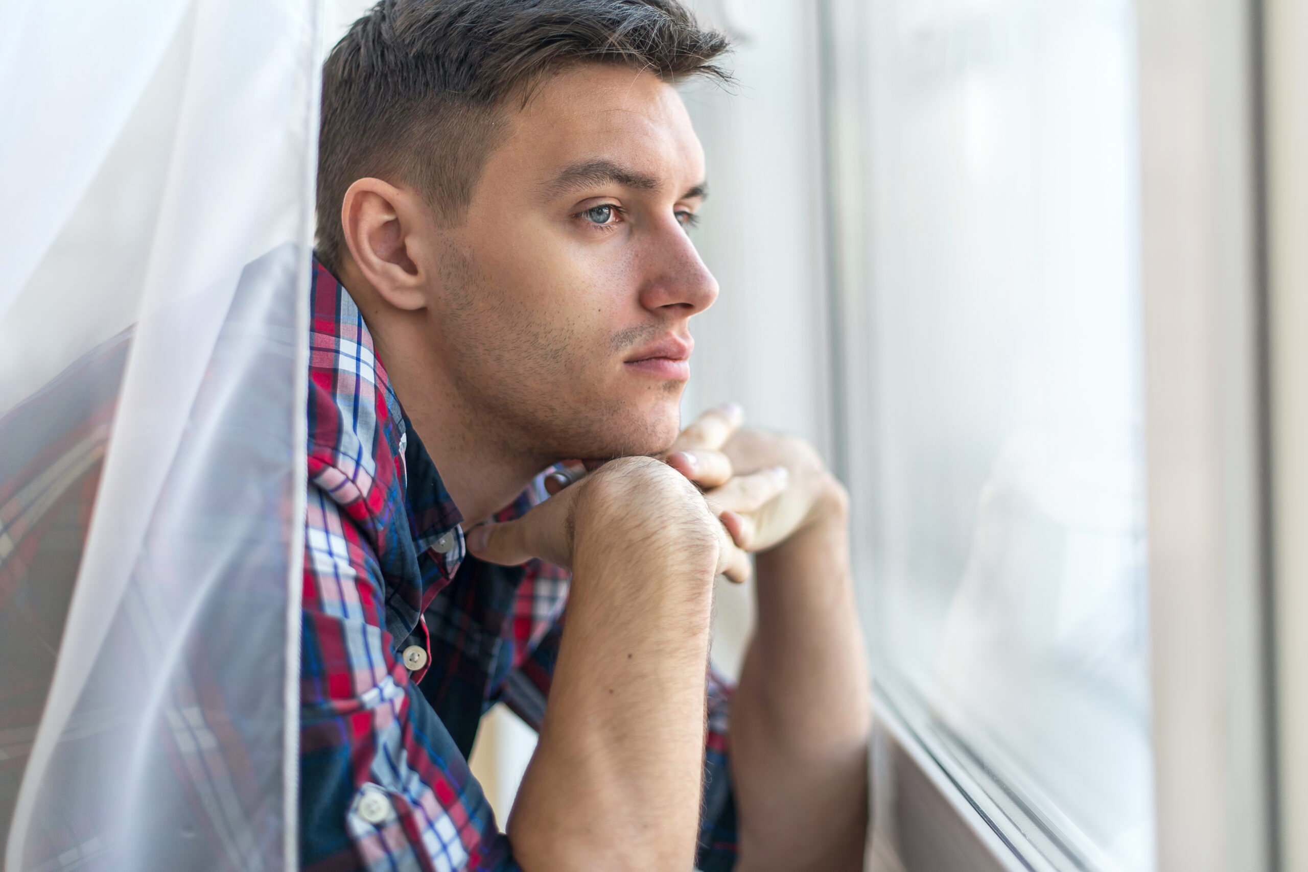 Handsome pensive man guy watching through the window concept sadness sorrow pain waiting.