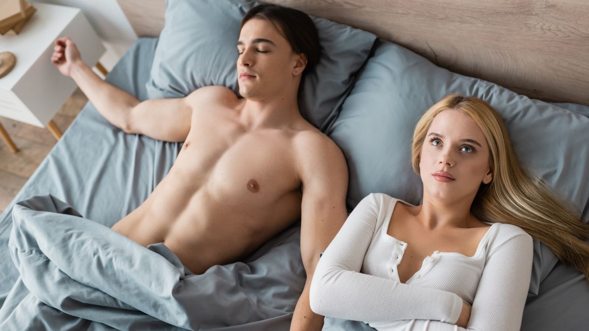 Woman in bed with a man looking like she regrets it