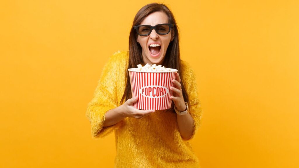woman holding pop corn with sun glasses on for a movie -